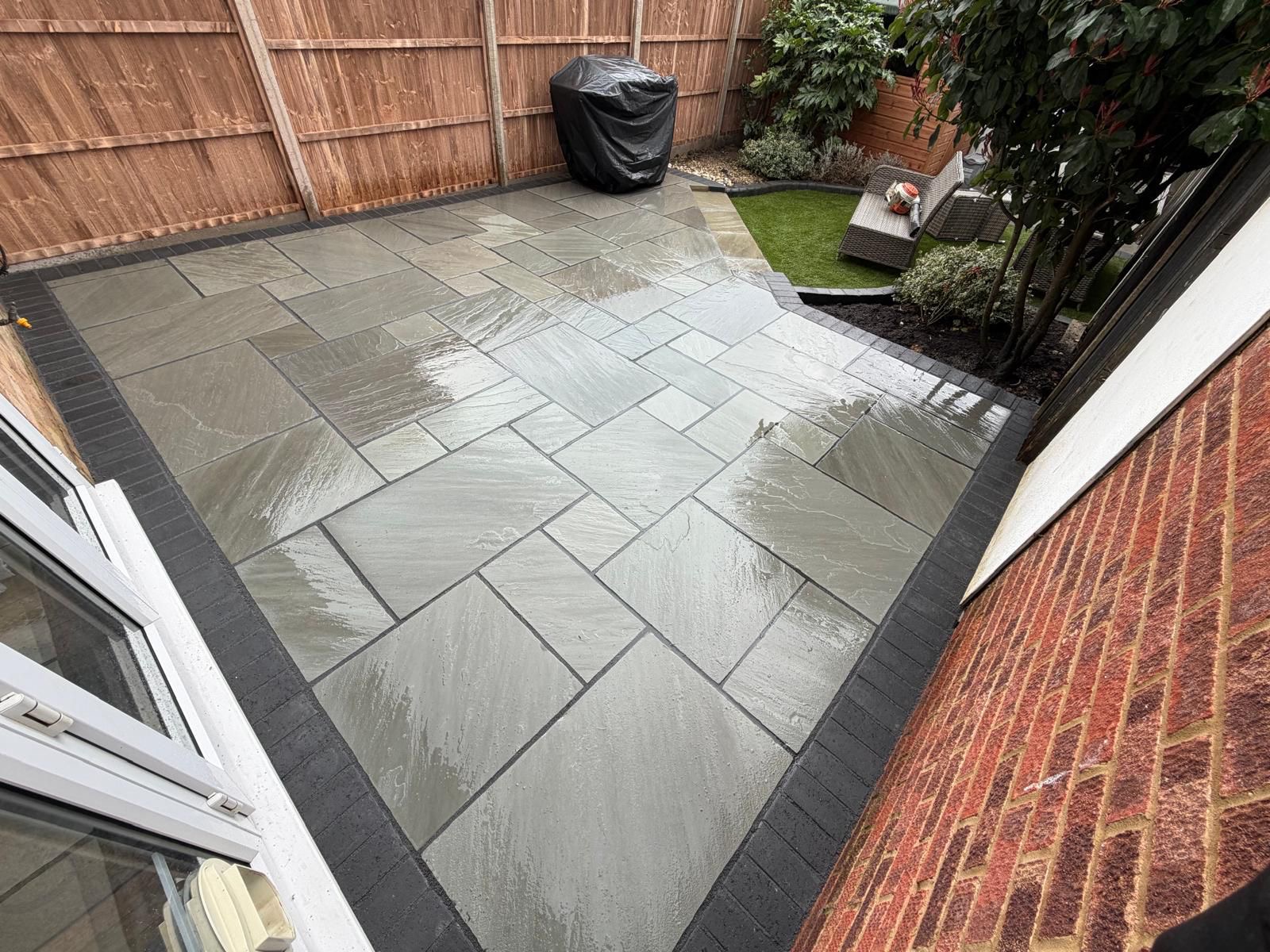 Laura's new Indian sandstone patio with charcoal brick edging